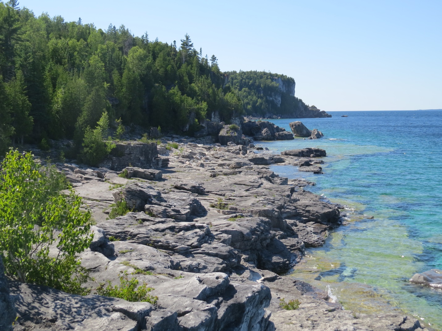 Another photo of the shoreline along Little Cove. The dolomite rock dominates the shoreline and the large cliffs are visible in the background.  